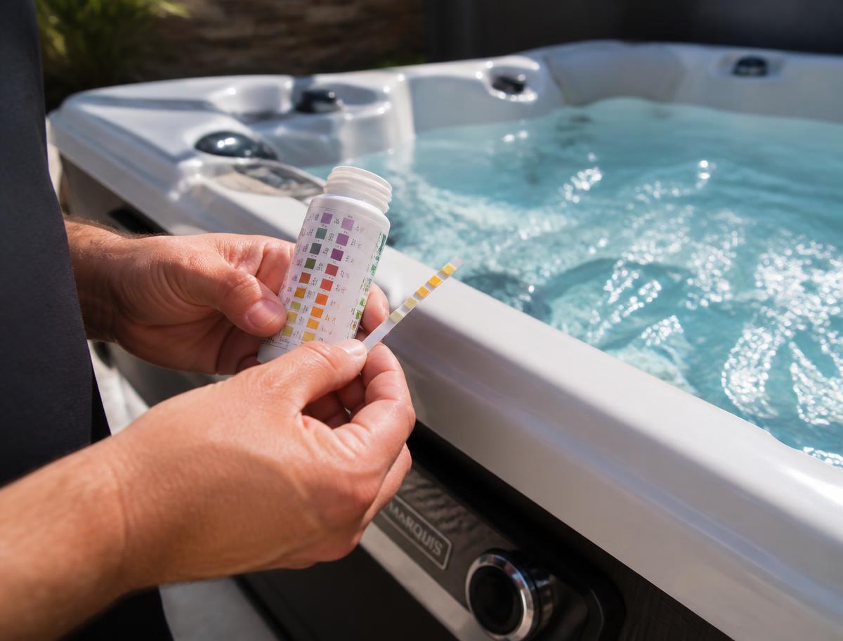 Technician testing spa water during a hot tub repair visit